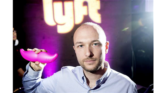 In this Monday, Jan. 26, 2015, file photo, Logan Green, co-founder and chief executive officer of Lyft, displays his company's 'glowstache' during a launch event in San Francisco. On Monday, Jan. 4, 2016, General Motors Co. announced it is investing $500 million in ride-sharing company Lyft Inc. GM gets a seat on Lyft’s board as part of the partnership, which could speed the development of on-demand, self-driving cars. (AP Photo/Noah Berger, File)