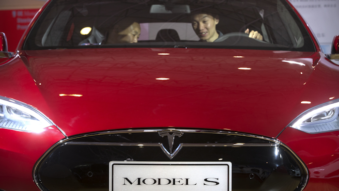 In this Monday, April 25, 2016, file photo, a man sits behind the steering wheel of a Tesla Model S electric car on display at the Beijing International Automotive Exhibition in Beijing. Tesla said Thursday, June 9, 2016, that it has started selling a cheaper version of its Model S car in an attempt to make its electric vehicles more affordable for more people. The new version, called the Model S 60, starts at $66,000. An all-wheel drive version of the Model S 60 will start at $71,000. Both cost less that the current Model S 90D, which starts at $89,500. (AP Photo/Mark Schiefelbein, File)
