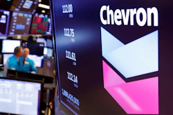 This Oct. 8, 2019, file photo shows the logo for Chevron on the floor of the New York Stock Exchange. Chevron Corp. reports financial results Friday, Nov. 1. Chevron said Tuesday, Dec. 10, it will book a charge of at least $10 billion because lower long-term prices for oil and natural gas are making some projects less valuable.