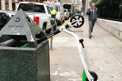 In this photo taken May 14, 2018, a man walks past an electric scooter that was dumped into a trash can in San Francisco. Tired of San Francisco streets being used as a testing ground for the latest delivery technology and transportation apps, city leaders are considering requiring businesses to get permits before trying out new high-tech ideas in public.