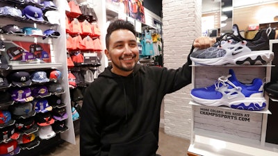 Victor Duran, a co-manager of a sports apparel store at the Southcenter mall, south of Seattle, poses for a photo at the store, Wednesday, Dec. 11, 2019, in Tukwila, Wash. Duran, 23, said he makes about $52,000 a year and doesn't get overtime, but is required to work at least 45 hours per week, and up to 60 during the holidays. Duran is one employee who could benefit from new overtime rules in Washington state, which will allow hundreds of thousands of workers who have been exempt to begin collecting when they work more than 40 hours per week.