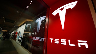 In this Saturday, Feb. 9, 2019, file photograph, a sign bearing the company logo stands outside a Tesla store in Cherry Creek Mall in Denver. Federal investigators have found that a 2018 crash and fire in Florida that killed the teenage driver of a Tesla Model S and a passenger was due to the car traveling at over 100 miles per hour on a curve. The National Transportation Safety Board says in a report released Thursday, Dec. 19, 2019 that the battery-powered car erupted in flames after colliding with a wall. The two 18-year-olds were trapped in the car.