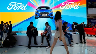 In this April 25, 2018, file photo, attendees visit the Ford booth during Auto China 2018 show held in Beijing, China. China’s government says it will postpone planned punitive tariffs on U.S.-made automobiles and other goods following an interim trade deal with Washington.Sunday, Dec. 15, 2019’s announcement came after Washington agreed to postpone a planned tariff hike on $160 billion of Chinese goods and to cut in half penalties that already were imposed.