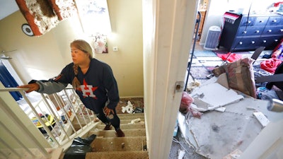 Maria Hernandez climbs her stairwell as she and her family worked to move their belongings out as they sifted through their damaged home in the Bridgeland Lane area of Houston, Sunday, Jan. 26, 2020, after the Watson Grinding Manufacturing explosion early Friday morning. Her ceiling, right, collapsed even further after overnight rains.