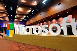 In this Nov. 30, 2016, file photo a man walks past a Microsoft sign at the annual Microsoft shareholders meeting in Bellevue, Wash. Microsoft on Thursday, Jan. 16, 2020, is announcing a plan to reduce its carbon footprint.