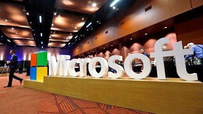 In this Nov. 30, 2016, file photo a man walks past a Microsoft sign at the annual Microsoft shareholders meeting in Bellevue, Wash. Microsoft on Thursday, Jan. 16, 2020, is announcing a plan to reduce its carbon footprint.