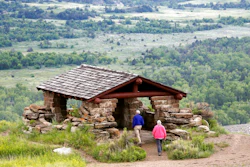 In this June 11, 2014, file photo, visitors hike to a stone lookout over the Little Missouri River inside the Theodore Roosevelt National Park, located in the Badlands of North Dakota. Anemic funding, alleged unpaid work and legal fights are hobbling developers of a proposed $800 million oil refinery near the park in western North Dakota. But the project manager for Meridian Energy Group's Davis Refinery, which has drawn criticism from environmental groups and others who worry it would add to pollution near the national park, insists it will be built.