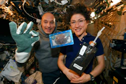 In this photo made available by U.S. astronaut Christina Koch via Twitter on Dec. 26, 2019, she and Italian astronaut Luca Parmitano pose for a photo with a cookie baked on the International Space Station. The results are finally in for the first chocolate chip cookie bake-off in space.