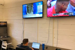 In this undated image provided by Cameron MacMillan, Brian Hourigan works at the Better Collective Tennessee, RotoGrinders.com office in downtown Nashville, Tenn., as NCAA college basketball plays on a television screen above. Sports can be a distraction at work the first few months of the year as pro football and college basketball hold their premier events. Business owners have to make a choice, whether, like McMillan at RotoGrinders.com, they'll allow or encourage staffers to enjoy the moment, or demand that everyone focus on work.