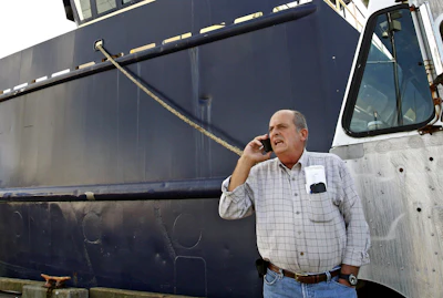 In this Oct. 14, 201, file photo, Carlos Rafael talks on the phone at Homer's Wharf near his herring boat F/V Voyager in New Bedford, MA. A Massachusetts company is slated to acquire in 2020 what's left of the boats once owned by Rafael, who was forced out of the industry after an elaborate fraud. The fishing magnate, known as the Codfather, was sentenced in 2017 to nearly four years in prison after pleading guilty to evading fishing quotas and smuggling money to Portugal.