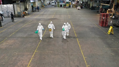 Workers wearing protective gears spray disinfectant as a precaution against the new coronavirus at Agricultural and Wholesale Products Center in Daegu, South Korea, Thursday, Feb. 20, 2020.