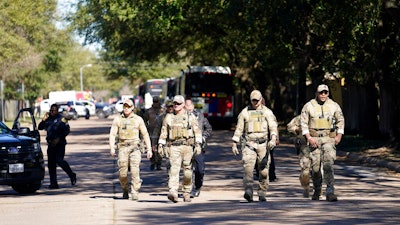 Law enforcement personnel walk along Rockcrest Rd. after an explosion occurred at nearby Watson Grinding and Manufacturing, Friday, Jan. 24, 2020, in Houston.
