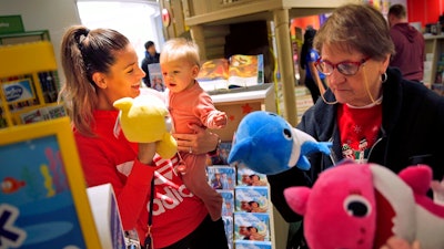 In this Dec. 9, 2019, file photo Melissa Rogan, left, and her daughter Renee, 9-months-old, browse the new Toys R Us store at a mall in Paramus, N.J. On Tuesday, Feb. 25, 2020, the Conference Board reports on U.S. consumer confidence for February.