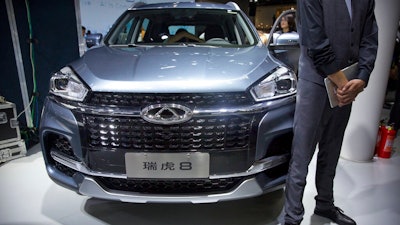 In this April 25, 2018, file photo a staff member stands next to a Tiggo 8 SUV by Chinese automaker Chery after a press conference at the China Auto Show in Beijing. A California company says it will build and sell Chinese-designed automobiles in the U.S. at the end of next year or early in 2022.