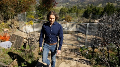 In this Tuesday, Feb. 25, 2020, photo, Jason Meek, whose Northern California wine country home was destroyed in 2017, walks through the remains of his home in Santa Rosa, Calif.