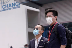 Visitors wear masks at the Singapore Airshow in Singapore Tuesday, Feb. 11, 2020. Singapore's air show began Tuesday with the usual ribbon cutting and displays of aerial prowess, but also with less typical warnings to industry and military figures attending to avoid handshakes and other close contact to avoid spreading a virus that has sickened tens of thousands of people.