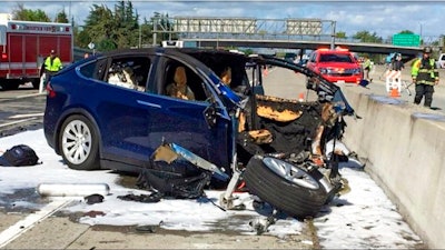 In this March 23, 2018, file photo provided by KTVU, emergency personnel work a the scene where a Tesla electric SUV crashed into a barrier on U.S. Highway 101 in Mountain View, Calif. The Apple engineer who died when his Tesla Model X crashed into the concrete barrier complained before his death that the SUV’s Autopilot system would malfunction in the area where the crash happened. The complaints were detailed in a trove of documents released Tuesday, Feb. 11, 2020, by the U.S. National Transportation Safety Board, which is investigating the March, 2018 crash that killed engineer Walter Huang.