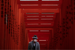 A man with a mask walk through torii gates at the Hie Shrine In Tokyo, Sunday, March 1, 2020.