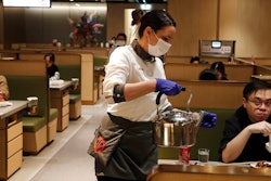 In this March 5, 2020, photo, a waitress of the Chinese restaurant Hot Pot serves customers in London.