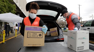 Volunteers Keshia Link, left, and Dan Peterson unload boxes of donated gloves and alcohol wipes from a car at a drive-up donation site for medical supplies at the University of Washington to help fight the coronavirus outbreak on Tuesday, March 24 in Seattle.