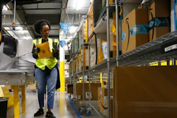In this Dec. 17, 2019, file photo, Tahsha Sydnor stows packages into special containers after Amazon robots deliver separated packages by zip code at an Amazon warehouse facility in Goodyear, Ariz. On Monday, March 16, 2020, Amazon said that it needs to hire 100,000 people across the U.S. to keep up with a crush of orders as the coronavirus spreads and keeps more people at home, shopping online.