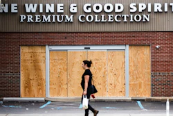 A pedestrian walks past a boarded up Wine and Spirits store in Philadelphia on Friday, March 20. Pennsylvania Gov. Tom Wolf directed all 'non-life-sustaining' businesses to close their physical locations late Thursday and said state government would begin to enforce the edict starting early Saturday.