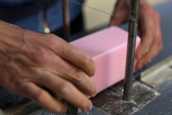 In this photo taken Monday March 16 2020, a factory worker cuts soap into bars at the Licorne soap factory in Marseille, southern France.