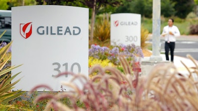 In this July 9, 2015, file photo, a man walks outside the headquarters of Gilead Sciences in Foster City, Calif. Gilead Sciences said Wednesday, March 25, 2020 it will give up the specialty status it received days earlier for its COVID-19 drug amid public outrage that the company was seeking to boost the profits of its treatment.