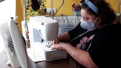 In this photo taken on Thursday, March 19, 2020, Sien Lagae, works on a mouth mask, meant to help protect from the spread of COVID-19, on her sewing machine at home in Torhout, Belgium. Lagae runs a social media group of volunteers who are making mouth masks for family and friends as well as hospital and caregivers in Belgium due to a shortage in supply of industrially made masks. For most people, the new coronavirus causes only mild or moderate symptoms, such as fever and cough. For some, especially older adults and people with existing health problems, it can cause more severe illness, including pneumonia.