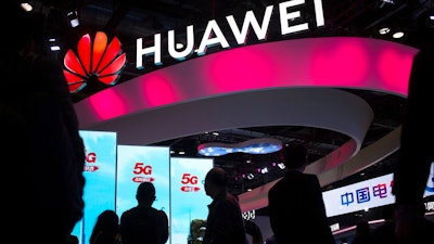 In this Oct. 31, 2019, file photo, attendees walk past a display for 5G services from Chinese technology firm Huawei at the PT Expo in Beijing. Chinese tech giant Huawei says its 2019 sales rose 19.1% over a year earlier despite U.S. sanctions that hampered its smartphone and network equipment businesses.