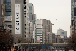 In this March 4, 2020, file photo, a large Tokyo 2020 Olympic banner hangs on the facade of a building in Tokyo. The tentacles of cancelling the Tokyo Olympics — or postponing or staging it in empty venues — would reach into every corner of the globe, much like the spreading virus that now imperils the opening ceremony on July 24.