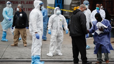 Medical workers wearing personal protective equipment due to COVID-19 concerns pause for rest before loading bodies onto a refrigerated container truck functioning as a makeshift morgue, Tuesday, March 31, 2020, at Brooklyn Hospital Center in Brooklyn borough of New York.