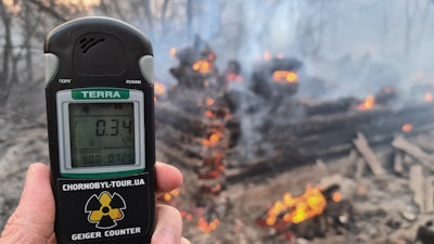A Geiger counter shows increased radiation level against the background of the forest fire burning near the village of Volodymyrivka in the exclusion zone around the Chernobyl nuclear power plant, Ukraine, Sunday, April 5, 2020.