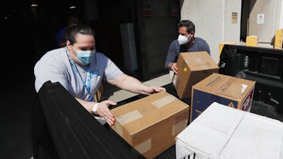 Christina Caldwell, left, of Henry Ford Population Health helps unload supplies with Matt Thatcher, who donated them from the Detroit Golf Club, Wednesday, April 8, 2020, in Detroit.