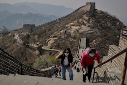Women wearing protective face masks to prevent the spread of the new coronavirus walk on a stretch of the Badaling Great Wall of China in Beijing, Tuesday, April 14, 2020.