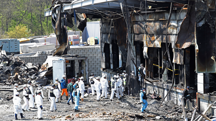 Police investigators enter to inspect a burnt construction site.