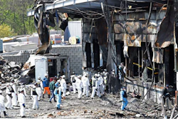 Police investigators enter to inspect a burnt construction site.