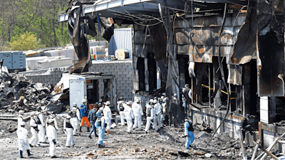 Police investigators enter to inspect a burnt construction site.