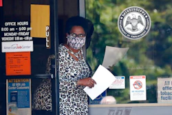 A masked worker at this state WIN job center in Pearl, Miss., holds an unemployment benefit application form as she waits for a client, Tuesday, April 21, 2020. The job centers lobbies are closed statewide to prevent the spread of COVID-19. However the continuing growth of unemployment demands and now additional assistance for self-employed, church employees, gig workers, and others who were previously ineligible for unemployment assistance has drawn some people to the centers for information and to obtain and submit unemployment benefit applications.