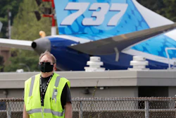A masked worker walks in view of a 737 jet at a Boeing airplane manufacturing plant.