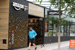 A person wearing a mask jogs past an Amazon Go store.