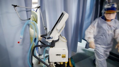 Nurse pulls a ventilator into an exam room.