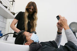 Leslie Musumecci checks a text while Emily Summerville rinses her hair Monday, May 11, 2020.