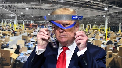 President Donald Trump looks through a face shield.