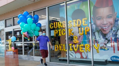 A Party City employee delivers balloons to a customer curbside, Wednesday, May 27, 2020, in Oceanside, N.Y. Long Island has become the latest region of New York to begin easing restrictions put in place to curb the spread of the coronavirus as it enters the first phase of the state's four-step reopening process.