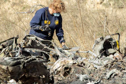 NTSB investigator Carol Hogan examines wreckage as part of the investigation of a helicopter crash near Calabasas, Calif., that killed former NBA player Kobe Bryant, his 13-year-old daughter, Gianna, and seven others, Jan. 27, 2020.