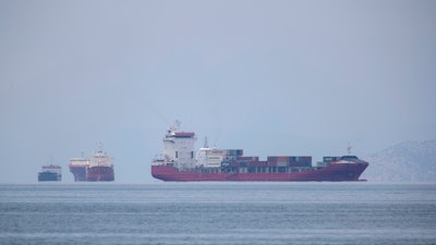 A cargo ship approaches the port of Piraeus as other ships are anchored.