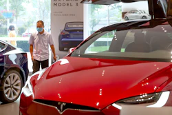 A customer wearing a face mask looks at automobiles in a Tesla car showroom in Beijing.