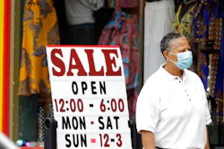 A woman walks past a boutique with a sale sign, Thursday, June 4, 2020, in Cleveland Heights, Ohio. The state says more than 34,000 Ohioans filed unemployment claims during the last week of May. That is the lowest figure since Ohio's stay-at-home orders depressed the economy and led to widespread layoffs.