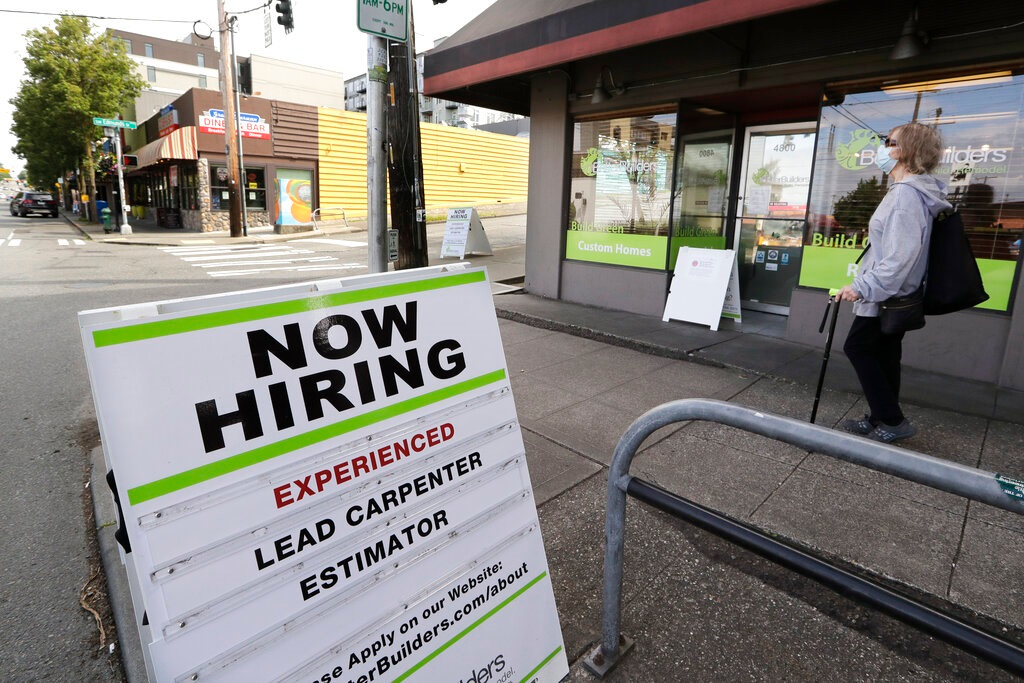 In this photo taken Thursday, June 4, 2020, a pedestrian wearing a mask walks past reader board advertising a job opening for a remodeling company, in Seattle. The U.S. unemployment rate fell to 13.3% in May, and 2.5 million jobs were added &mdash; a surprisingly positive reading in the midst of a recession that has paralyzed the economy and depressed the job market in the wake of the viral pandemic.